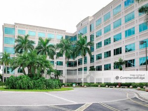 Exterior shot of Sawgrass Lake Center in Sunrise, Fla., a six-story building with glass and white concrete façade, surrounded by palm trees.
